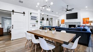 Una cocina moderna con comedor, un sofá y un televisor montado en la pared.