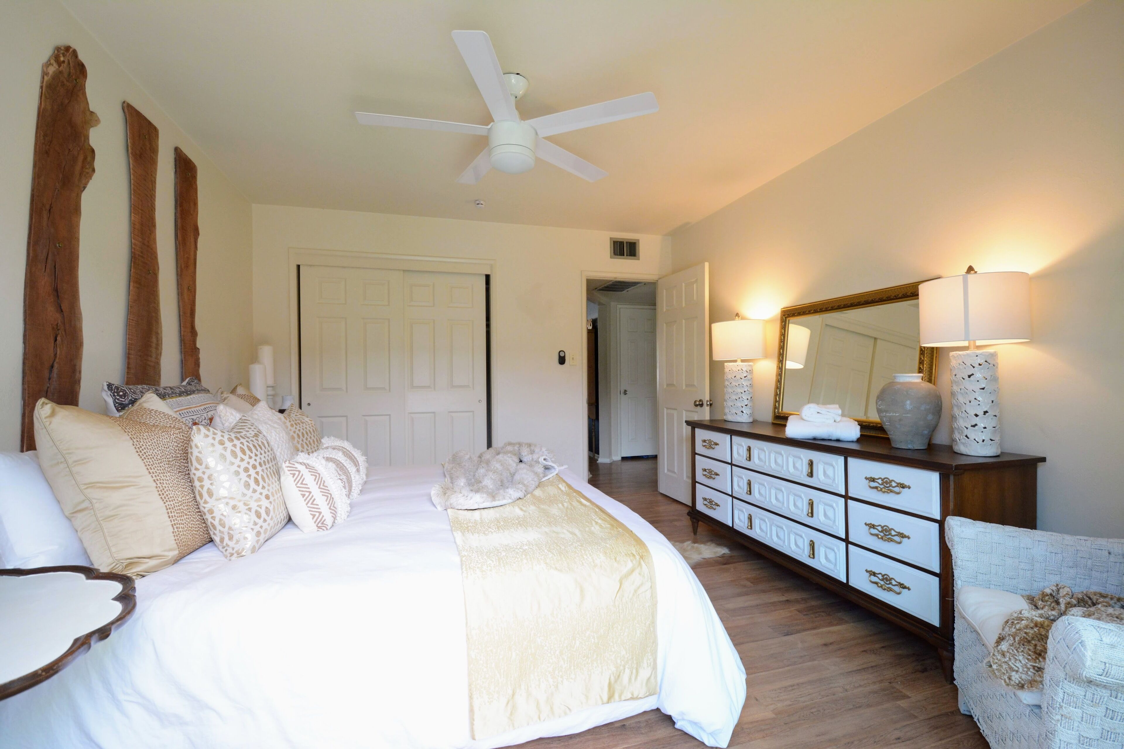 Un dormitorio con cama, cómoda, espejo y ventilador de techo.