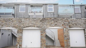 A two-story building with a stone facade and three white garage doors. - Slipway 16 (Wadebridge)