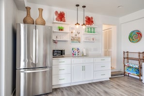 Una cocina moderna con refrigerador de acero inoxidable, armarios blancos y un banco de madera.