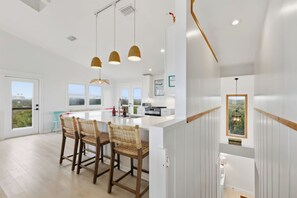 A modern kitchen with a central island, pendant lighting, and a view of the outdoors. - OCEANFRONT HOUSE, FRESHLY RESTORED BEACH, PET FRIENDLY, MINUTES TO ST AUGUSTINE! (Vilano Beach)
