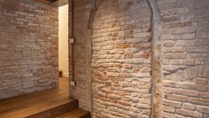 A narrow hallway with exposed brick walls and wooden steps leading to a door. - VELLUTO Luxury open space mezzanine and terrace self check in (Venezia)