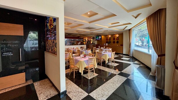 A restaurant with a checkered floor, wooden chairs, and a bar area with a TV. -  Hot Plaza Camarones | Love Hotel | Solo Adultos (Mexico City)