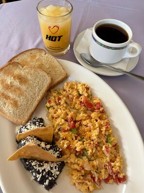 A breakfast plate with scrambled eggs, toast, and chilaquiles, a glass of orange juice, and a cup of coffee. -  Hot Plaza Camarones | Love Hotel | Solo Adultos (Mexico City)