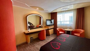 A hotel room with a bed, a TV, a desk, two chairs, and a mirror. -  Hot Plaza Camarones | Love Hotel | Solo Adultos (Mexico City)