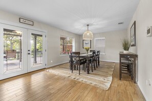 A dining area with a wooden table and chairs, a woven rug, and a pendant light. - Waterhouse- 4 Bed, 3 bath, SUP, Kayak,  Ping pong, Decks galore (Seguin)