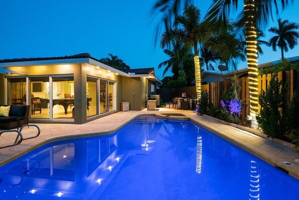 Una piscina con cerramiento de cristal, palmeras y un espacio exterior bien iluminado.