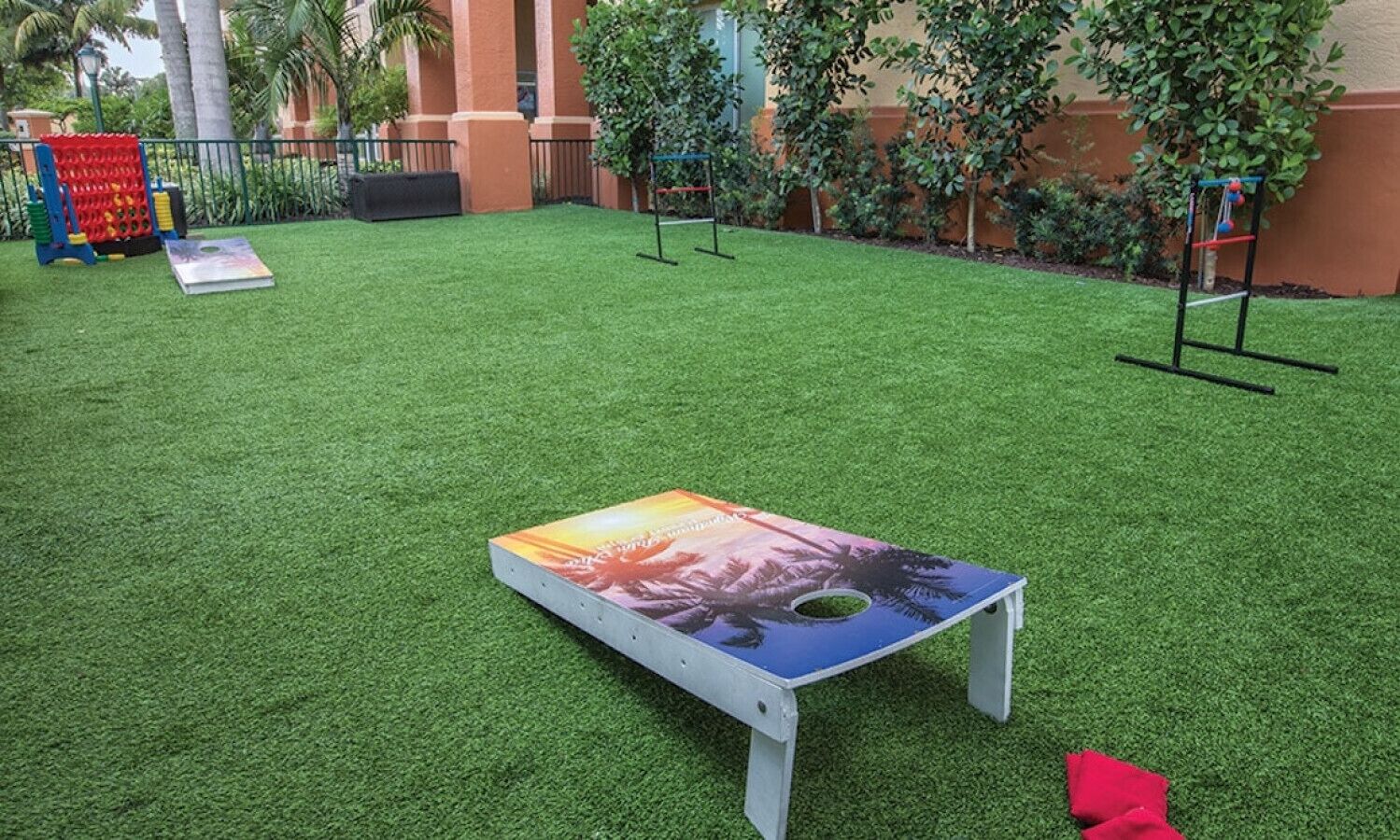 A small outdoor area with artificial grass, a colorful table, and a red object on the ground.
