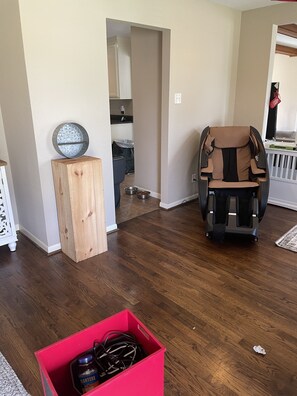 A living room with a massage chair, a wooden cabinet, and a red storage box.
