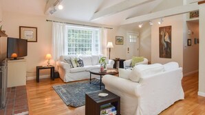 A living room with a sofa, a coffee table, a TV, and a lamp. - Pond Front Home with Private Dock! (Brewster)