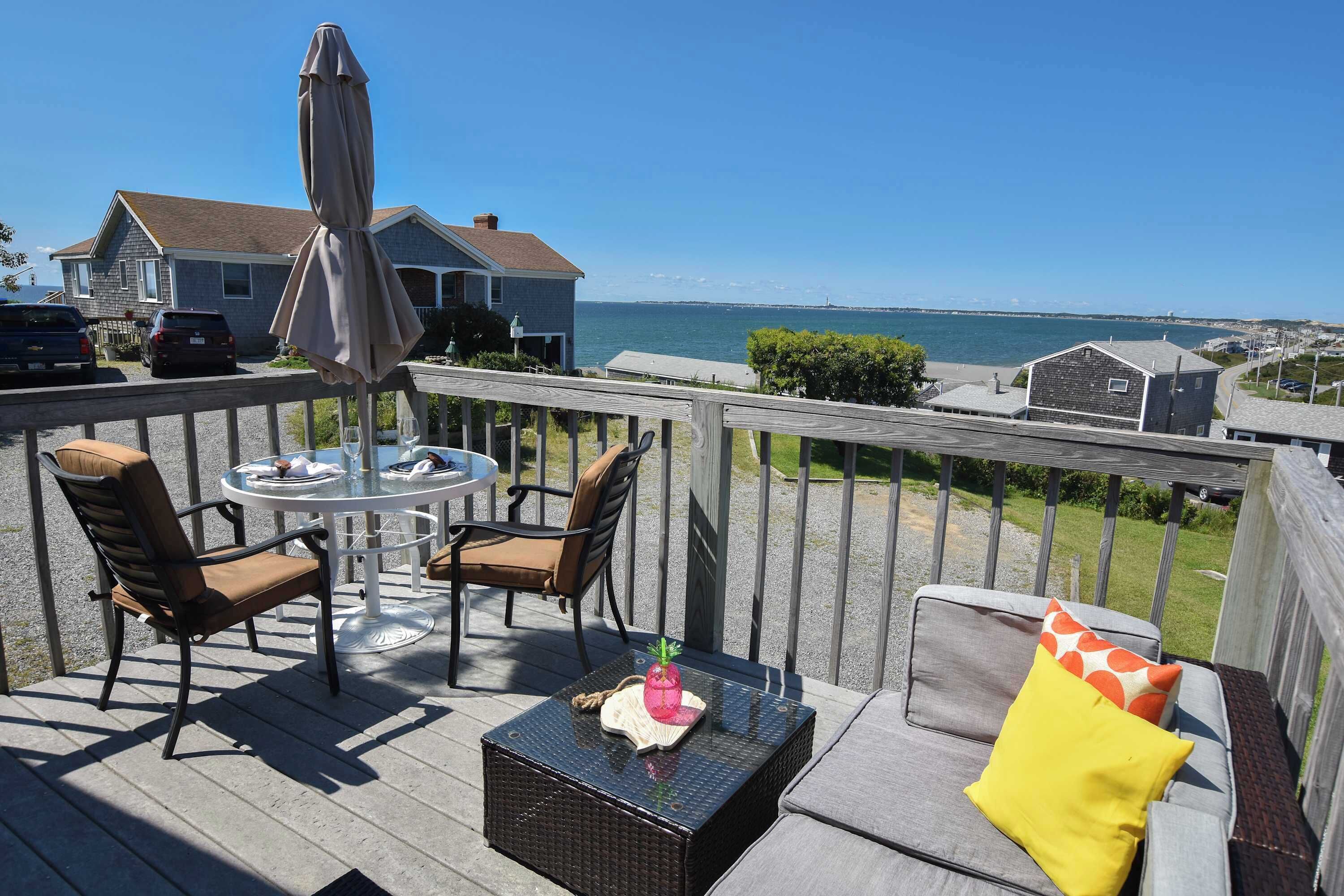 A deck with outdoor furniture, a table, and an umbrella.