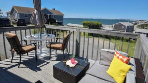 Um terraço com móveis de exterior, uma mesa e um guarda-sol.