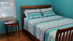Un dormitorio con una cama de madera, una mesita y una ventana con persianas.
