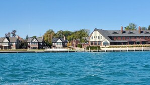 Una propiedad frente al agua con un muelle, un edificio grande con techo a dos aguas y una hilera de casas más pequeñas.