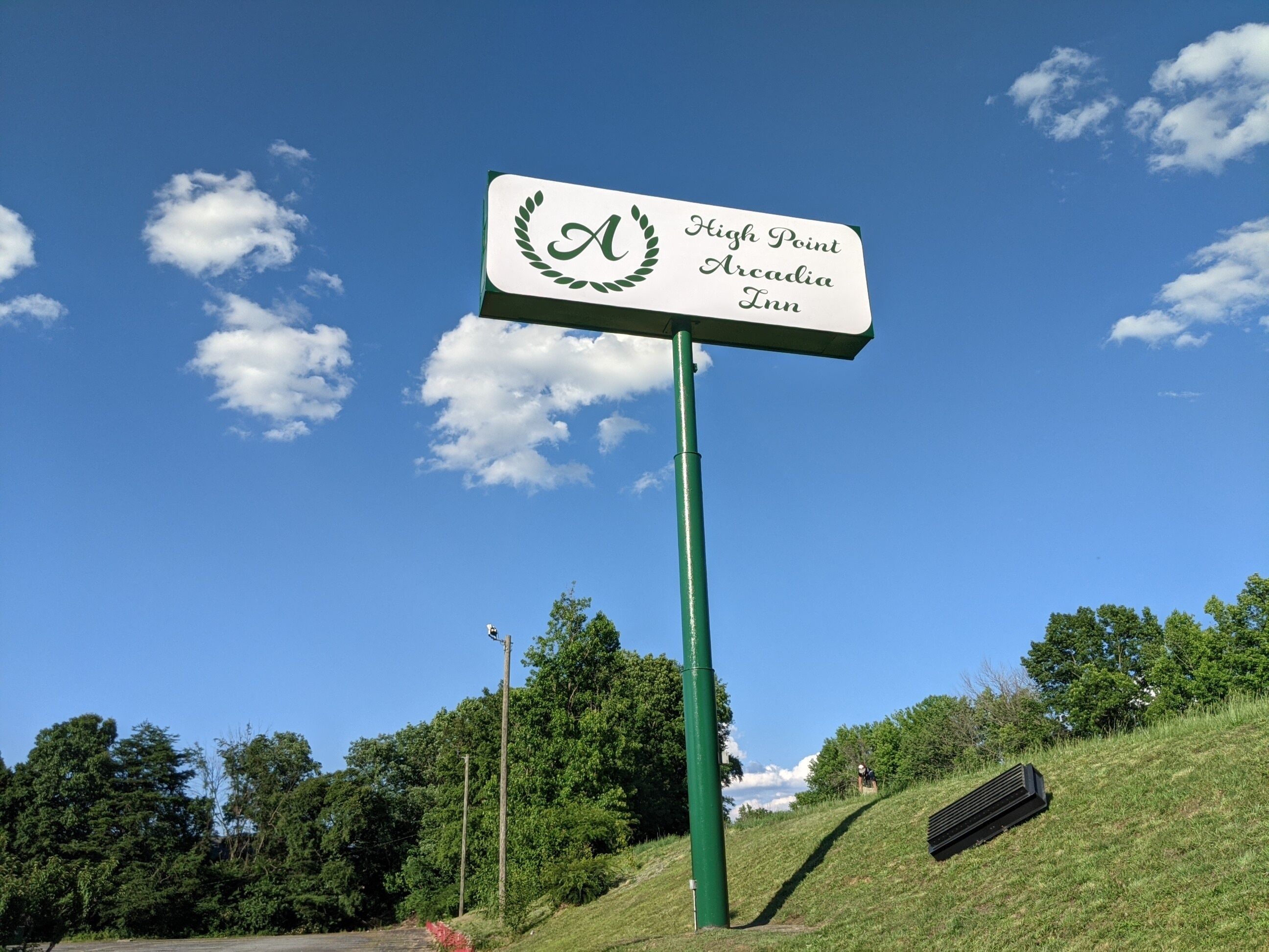 Ein Schild für das High Point Arcadia Inn mit einem grünen Pfosten.