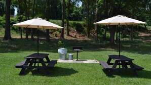 Two picnic tables with umbrellas in a grassy area surrounded by trees. - High Point Arcadia Inn (High Point)
