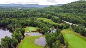 Ein Golfplatz mit mehreren Grüns, Wasserhindernissen und dichten Waldgebieten.
