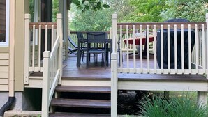Eine überdachte Veranda mit Holzterrasse, Sitzgelegenheit im Freien und Grill.