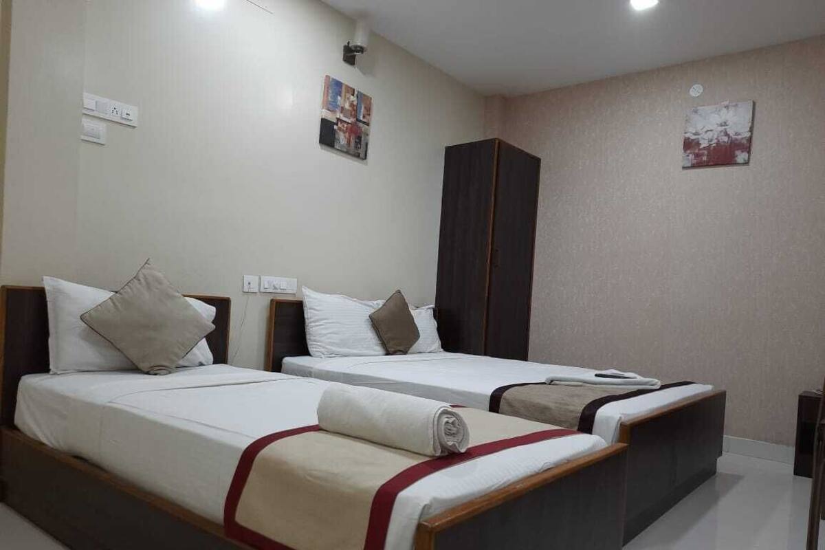 Una habitación de hotel con dos camas individuales, un armario y una mesita.