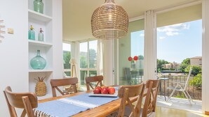 A dining area with a wooden table, chairs, and a wicker pendant light.