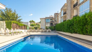 A swimming pool with lounge chairs and a building in the background.