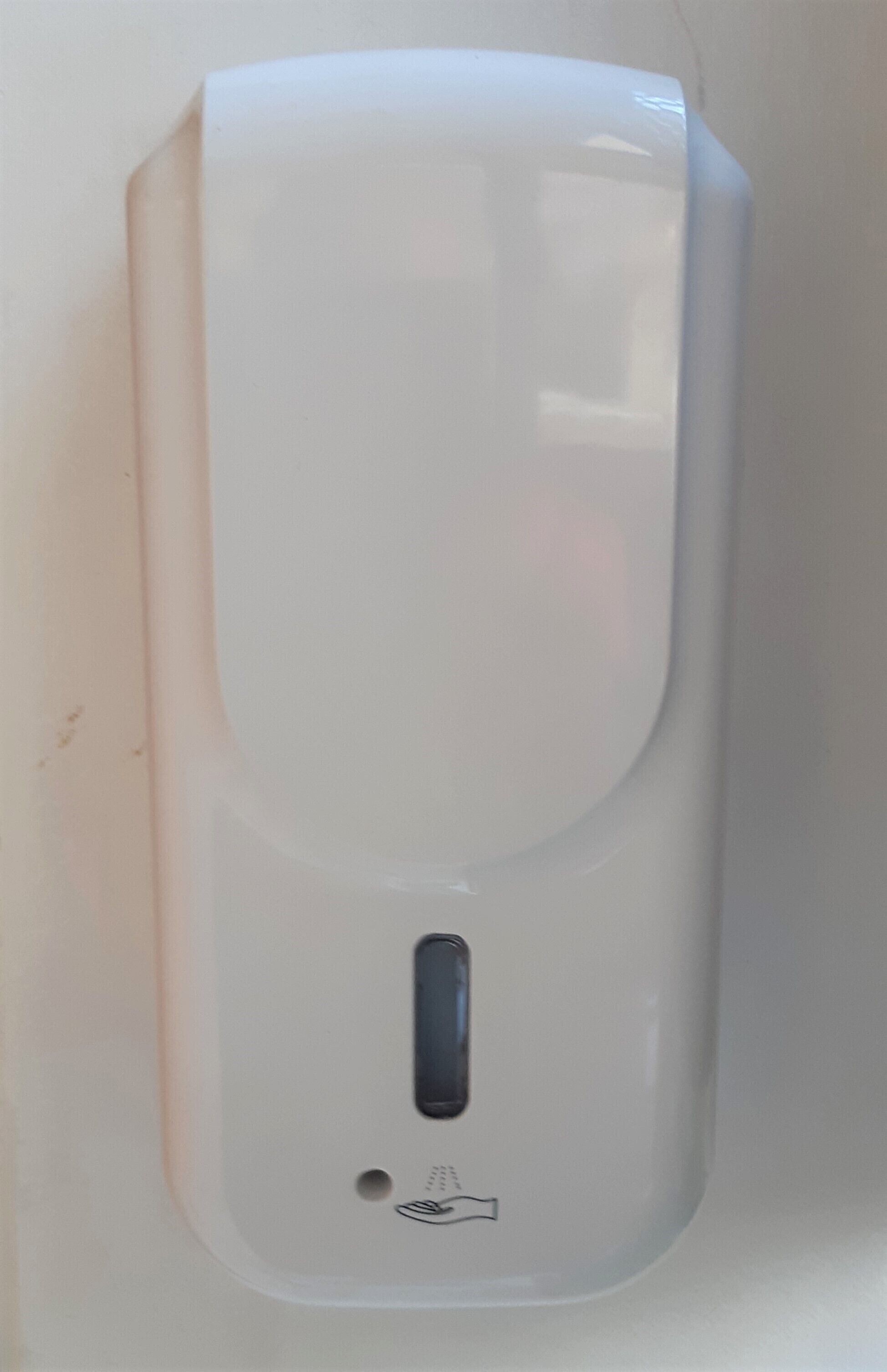 En vit, väggmonterad tvåldispenser med en enda knapp och ett litet hål under den.
