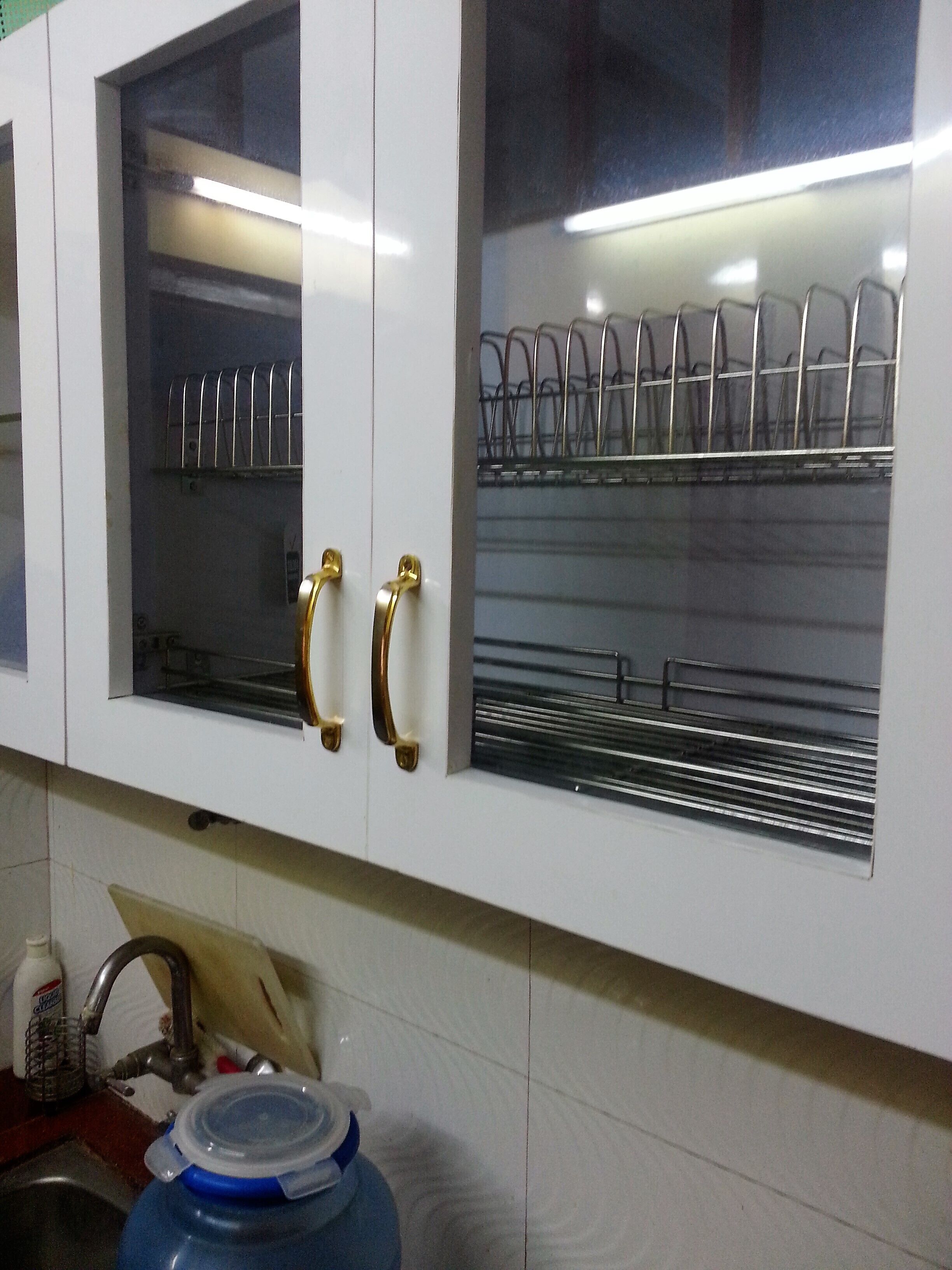 A kitchen with white cabinets, a stainless steel sink, and a blue water dispenser.
