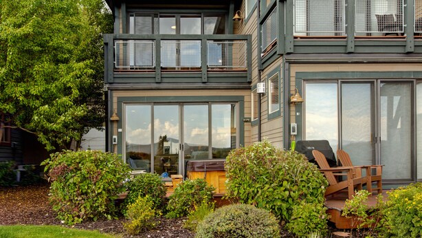 Een huis met twee verdiepingen, een balkon, een barbecue en terrasmeubilair.