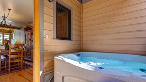 Ein Holzblockhaus-Interieur mit Whirlpool, Holzmöbeln und einem Fenster.