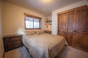 A bedroom with a bed, wooden wardrobe, nightstand, and a window.
