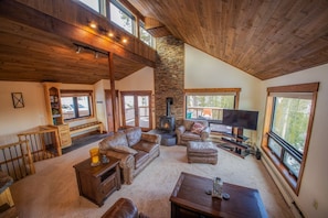 A spacious living room with a stone fireplace, leather sofas, and a large TV.