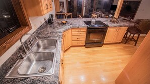 Una cocina moderna con encimeras de granito, armarios de madera y un lavamanos de acero inoxidable.