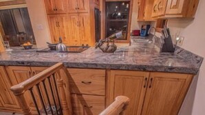 Una cocina con armarios de madera, encimera de granito y una escalera de madera.