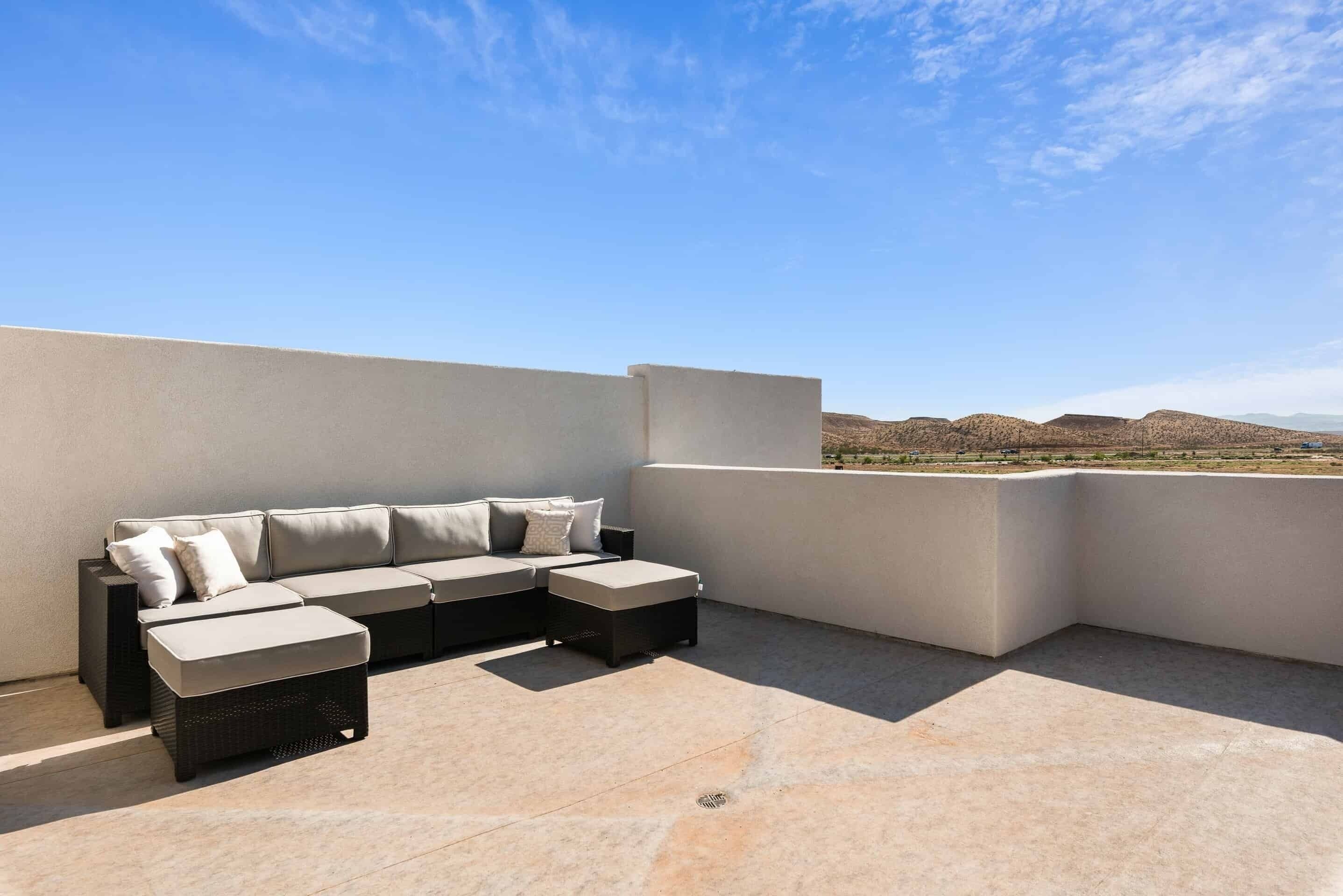 A rooftop terrace with a sectional sofa and a small table, offering a view of the surrounding landscape.