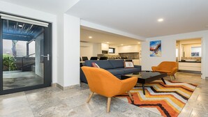 A modern living room with a sofa, two armchairs, a coffee table, and a colorful rug. - Across The Road From The Beach (Inverloch)