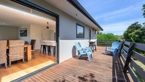 Une maison moderne dotée d’une terrasse en bois, d’un espace salon extérieur et d’un coin repas.