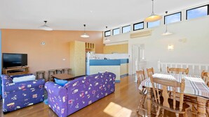 A spacious living area with a sofa set, a dining table, and a kitchen in the background. - Picture Perfect on Pier (INVERLOCH)