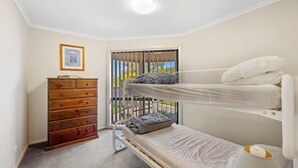A small, well-lit room with a bunk bed, a wooden dresser, and a door leading to a balcony. - Picture Perfect on Pier (INVERLOCH)