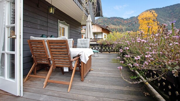 A wooden deck with outdoor furniture, a partially open door, and a view of a mountain landscape. - Vacation apartment "Seeberg - House Annamirl" with beautiful south terrace (Bayrischzell)