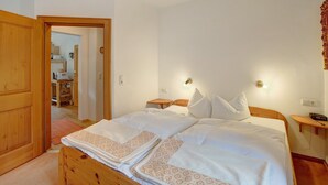 A bedroom with a wooden bed, white bedding, two bedside tables, a nightstand, and a wall-mounted lamp. - Vacation apartment "Seeberg - House Annamirl" with beautiful south terrace (Bayrischzell)
