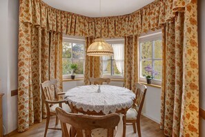 A dining area with a round table, chairs, and a lace tablecloth.