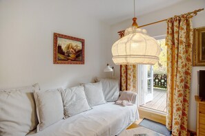 A room with a sofa, a lamp, a painting, and a window with curtains.