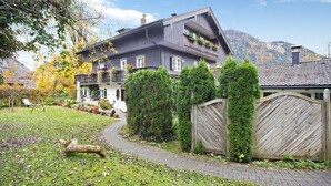 A two-story house with a garden pathway, a wooden fence, and a mountain backdrop. - Vacation apartment "Seeberg - House Annamirl" with beautiful south terrace (Bayrischzell)
