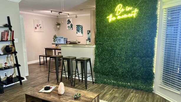 Ein modernes Wohnzimmer mit Couchtisch aus Holz, einer Bar und einer grünen Wand mit einer Neonreklame.