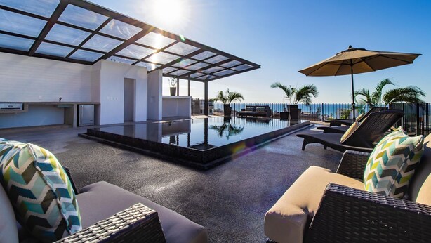 A rooftop pool area with lounge chairs and a glass-enclosed patio. - Penthouse Condo with Private Rooftop Terrace. Short walk to the Beach & Malecón. (Puerto Vallarta)