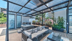 A modern outdoor living space with a glass-enclosed patio, a hot tub, and a sofa set. - Penthouse Condo with Private Rooftop Terrace. Short walk to the Beach & Malecón. (Puerto Vallarta)