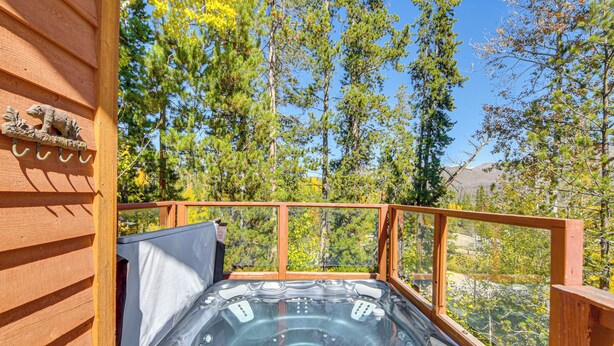 Ein Whirlpool auf einer Holzterrasse mit Blick auf Bäume und Berge.