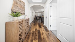 A hallway with wooden flooring, white walls, and a wooden cabinet with a plant. - Family-Friendly Home Near Vineyards & Dtwn Newberg (Newberg)