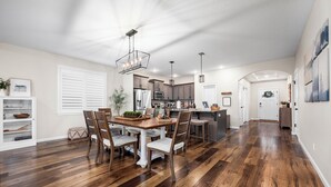 A spacious kitchen with wooden flooring, a dining area with a wooden table and chairs, and pendant lighting. - Family-Friendly Home Near Vineyards & Dtwn Newberg (Newberg)