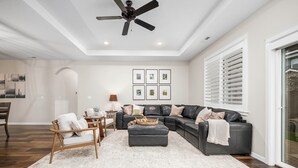 A spacious living room with a dark leather sectional sofa, a wooden chair, and a white rug. - Family-Friendly Home Near Vineyards & Dtwn Newberg (Newberg)